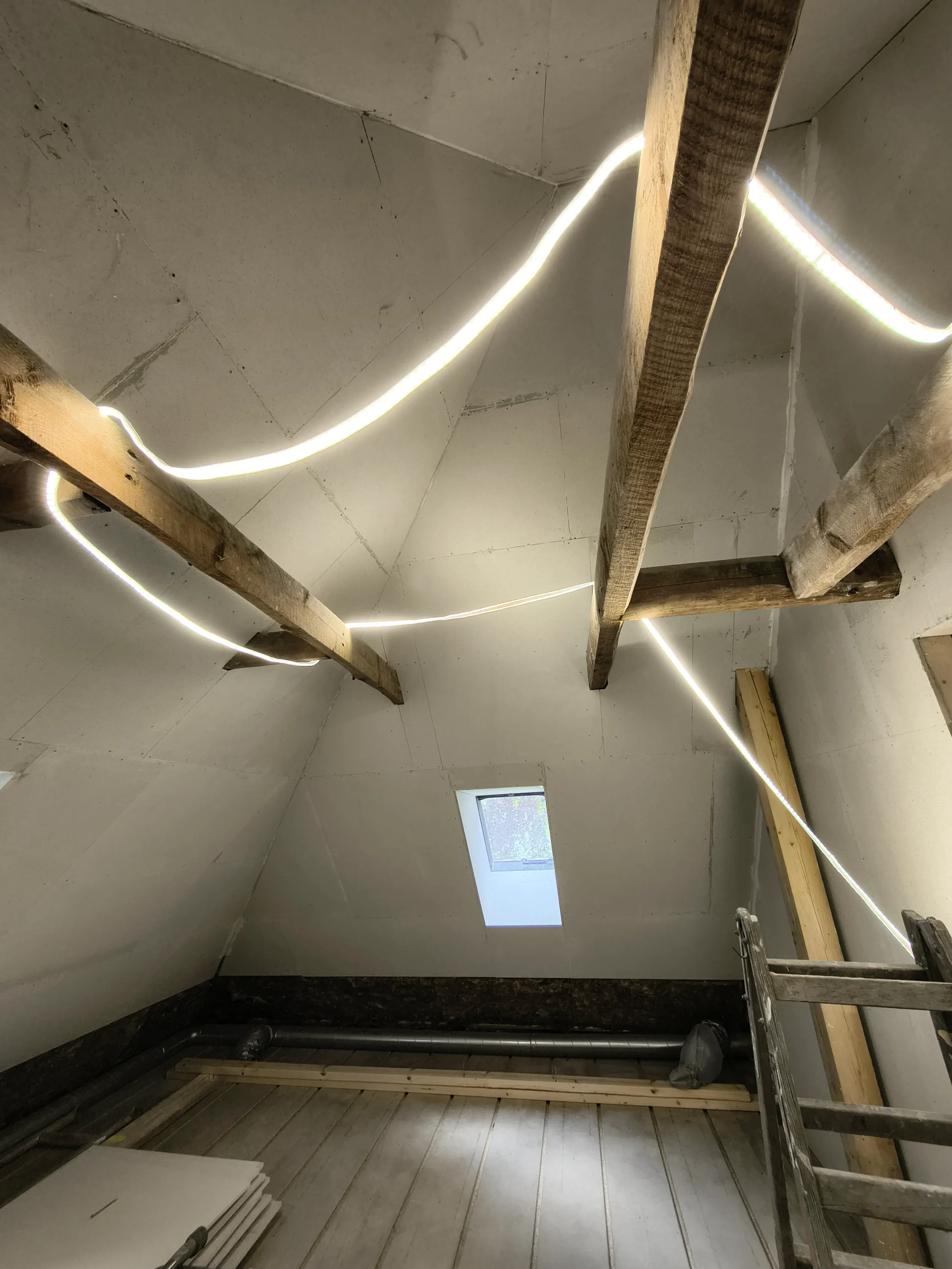 Renoveret loft med LED-belysning og træbjælker