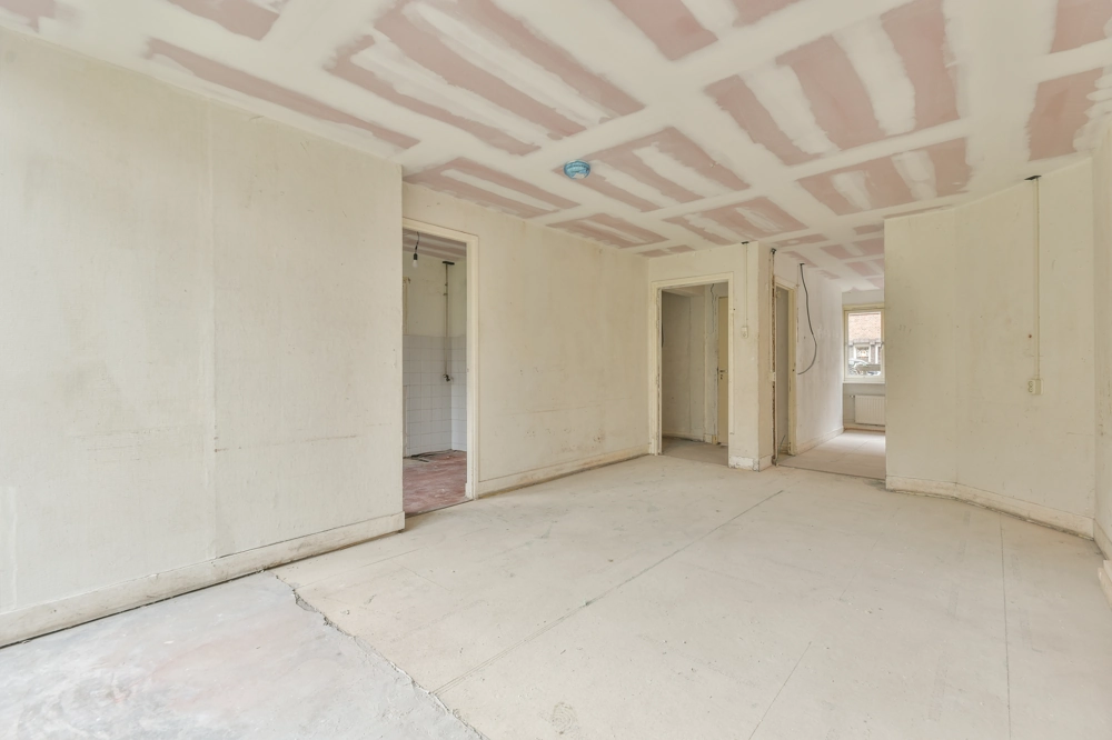Tomt rum med spartlede vægge og loft, klar til indvendig renovering og maling